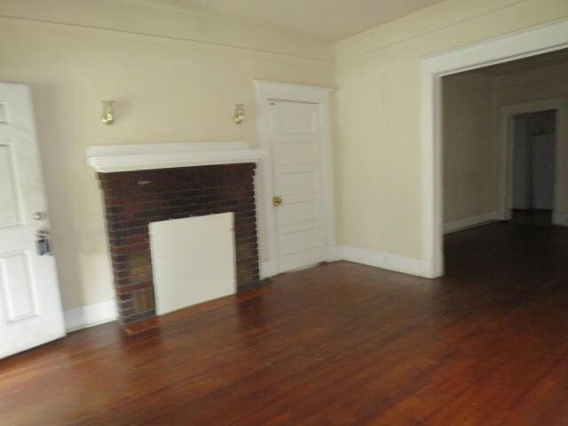 1307 Beman St, Augusta, GA 30904 - unfurnished living room with wood finished floors and a brick fireplace