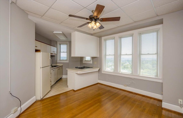 2068 Walton Way, Augusta, GA 30909 - kitchen featuring white appliances, light wood finished floors, white cabinets, a peninsula, and a paneled ceiling