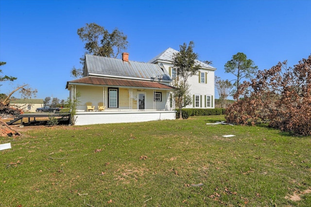 back of property with a yard and covered porch