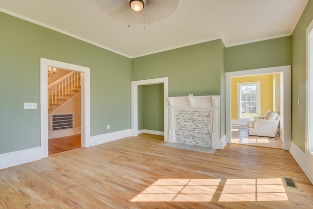 unfurnished living room featuring ceiling fan with notable chandelier, light wood-type flooring, and crown molding