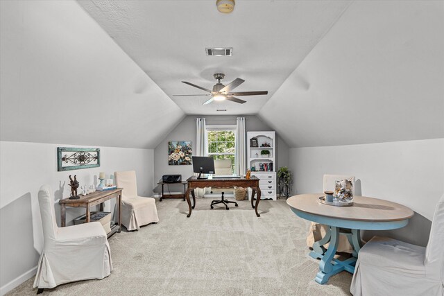 carpeted home office featuring a textured ceiling, vaulted ceiling, and ceiling fan