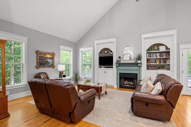 living room with built in features, high vaulted ceiling, and light hardwood / wood-style flooring