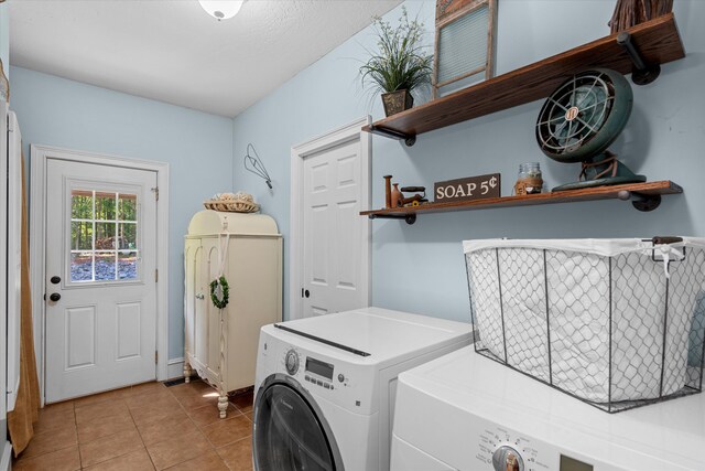 laundry room with washing machine and dryer, light tile patterned floors, and a textured ceiling