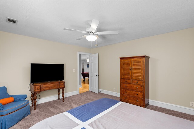 carpeted bedroom featuring ceiling fan and a textured ceiling