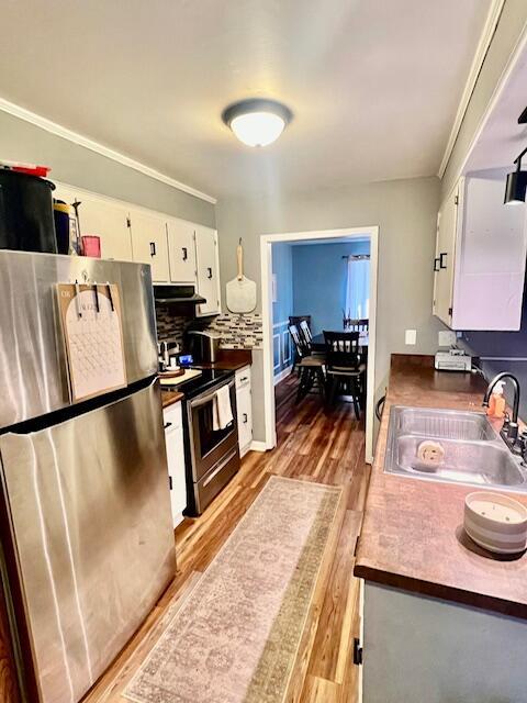 kitchen featuring sink, hardwood / wood-style floors, decorative backsplash, white cabinets, and appliances with stainless steel finishes