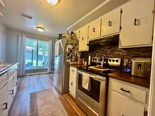 kitchen featuring stainless steel appliances, white cabinetry, tasteful backsplash, and hardwood / wood-style flooring