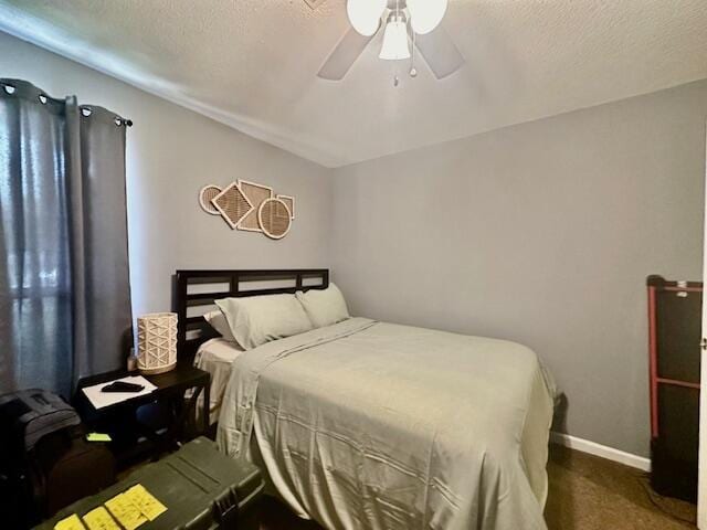 bedroom featuring a textured ceiling, dark carpet, and ceiling fan