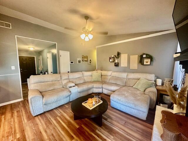 living room featuring ceiling fan, hardwood / wood-style floors, and lofted ceiling