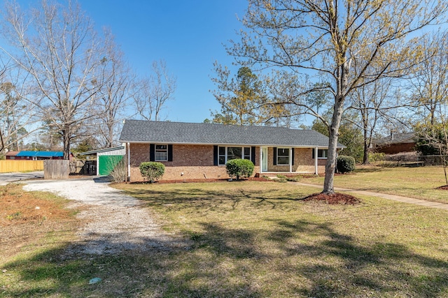 view of front of house with a front yard, fence, brick siding, and driveway