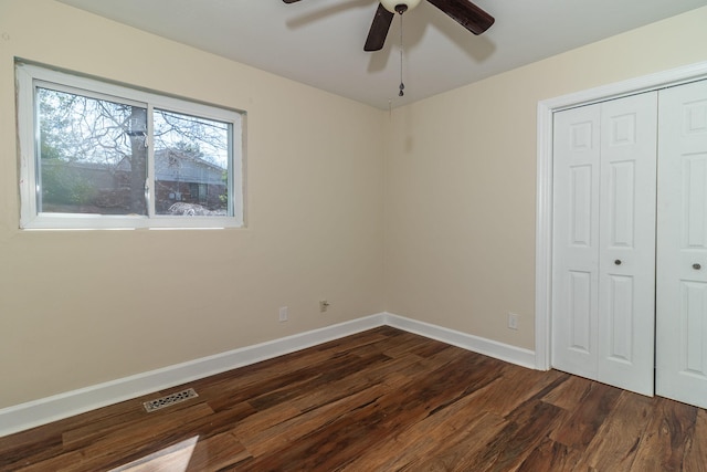 unfurnished bedroom featuring visible vents, a closet, baseboards, ceiling fan, and dark wood-style flooring