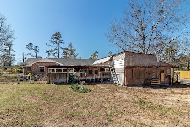 rear view of property featuring a lawn and fence