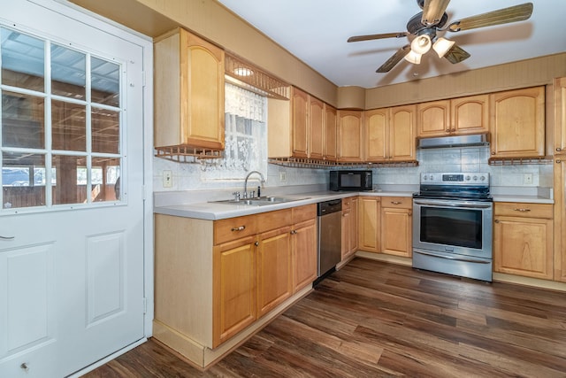 kitchen with a sink, light countertops, dark wood-type flooring, under cabinet range hood, and appliances with stainless steel finishes