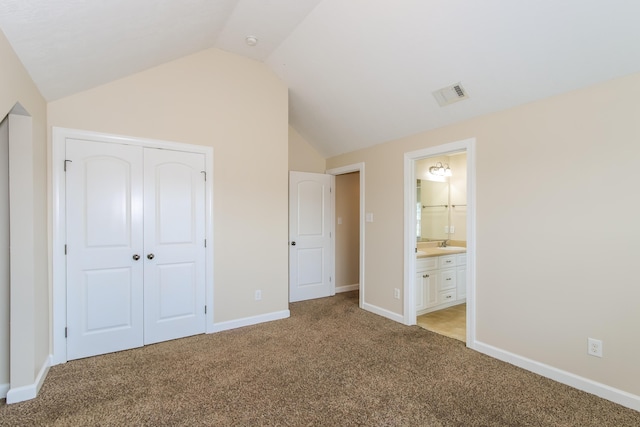 unfurnished bedroom featuring light carpet, connected bathroom, vaulted ceiling, and a closet