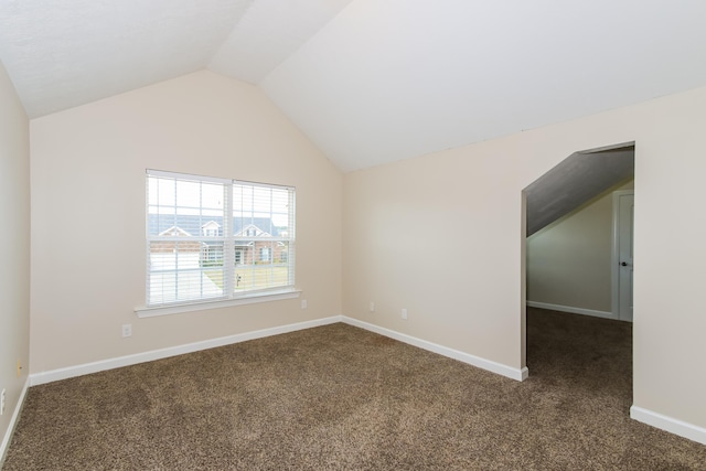 carpeted spare room with vaulted ceiling