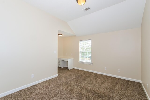 carpeted spare room with vaulted ceiling