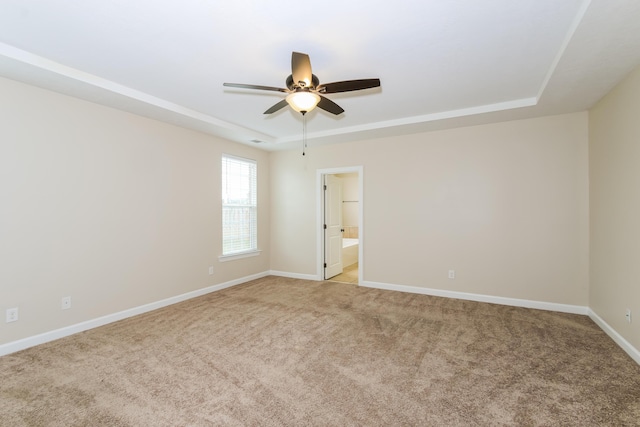 carpeted empty room featuring ceiling fan and a raised ceiling