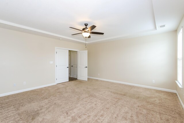 spare room with light colored carpet, a raised ceiling, and ceiling fan