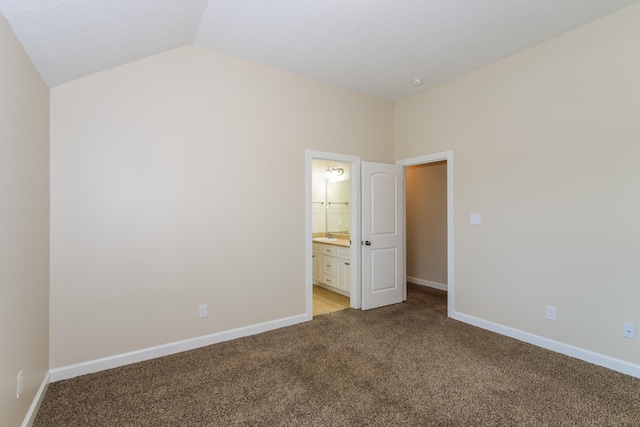 unfurnished bedroom featuring light carpet, ensuite bathroom, and lofted ceiling