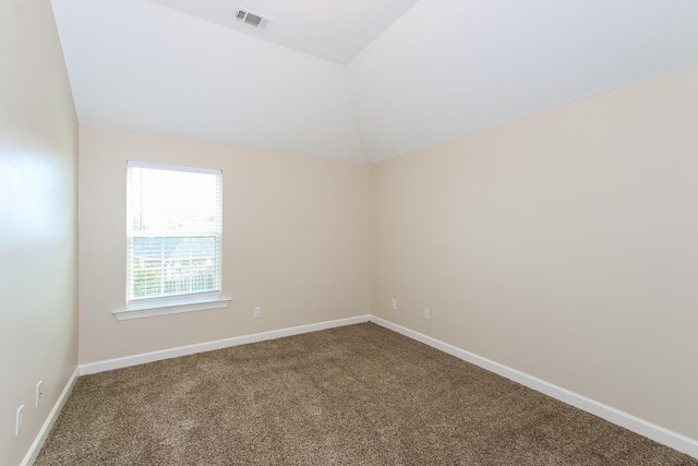 carpeted empty room with vaulted ceiling