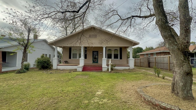 bungalow-style home with a front yard, fence, and covered porch