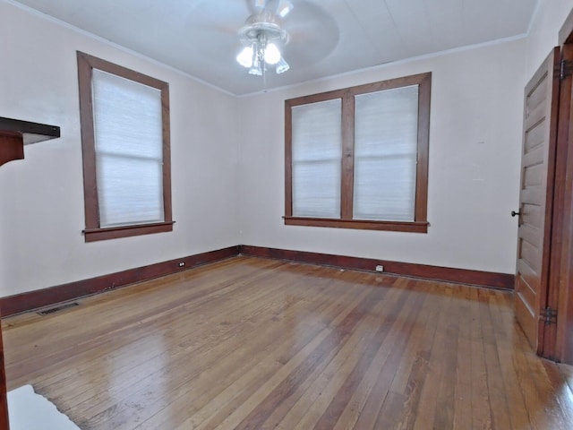 unfurnished room with visible vents, baseboards, ceiling fan, ornamental molding, and wood-type flooring
