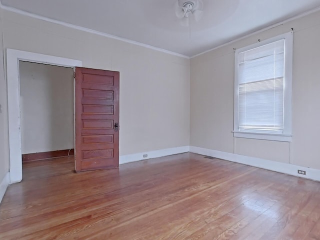 empty room with ceiling fan, baseboards, light wood finished floors, and ornamental molding