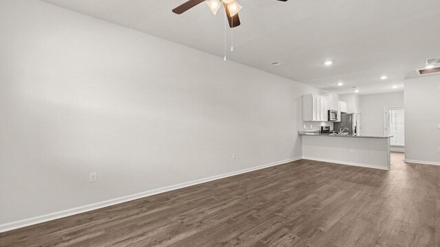 unfurnished living room featuring ceiling fan and dark hardwood / wood-style floors