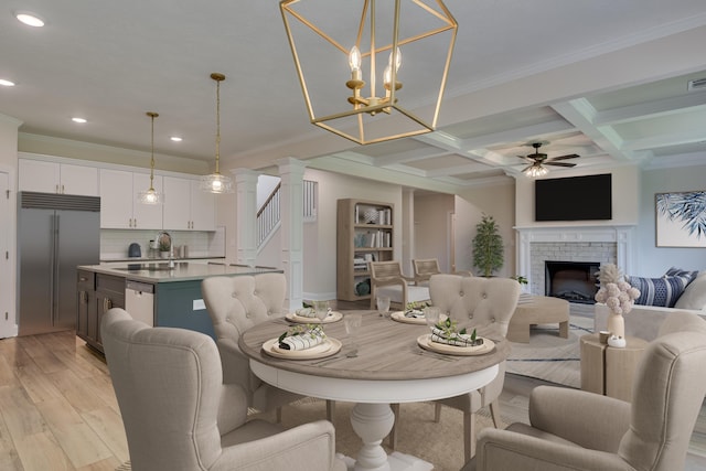 dining area featuring coffered ceiling, beam ceiling, crown molding, light wood-type flooring, and a fireplace