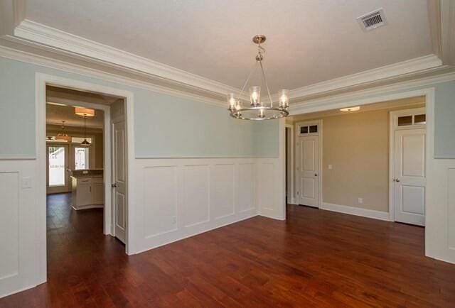 unfurnished room featuring an inviting chandelier, crown molding, visible vents, dark wood-style flooring, and wainscoting