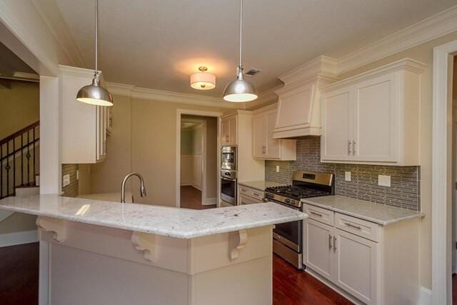 kitchen featuring a peninsula, a sink, stainless steel range with gas stovetop, white cabinetry, and backsplash