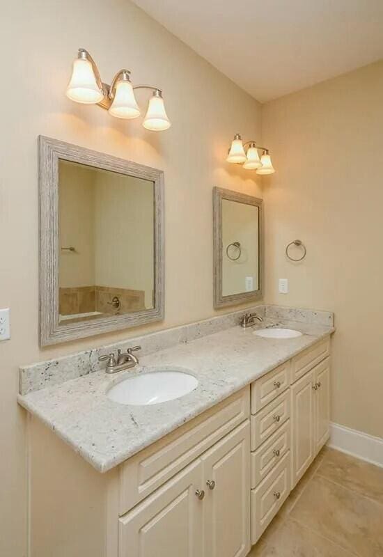 full bath featuring tile patterned floors, double vanity, baseboards, and a sink