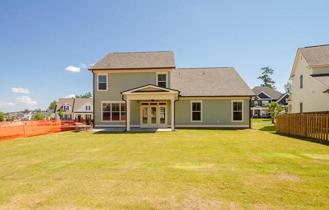 rear view of property with french doors, a yard, and fence