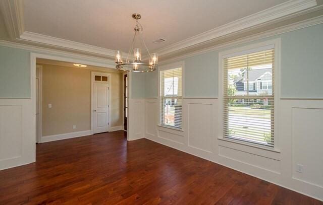 empty room with a decorative wall, an inviting chandelier, crown molding, and wainscoting