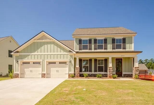 craftsman house featuring board and batten siding, driveway, a front lawn, and an attached garage