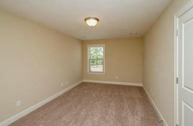 unfurnished room with carpet flooring and baseboards