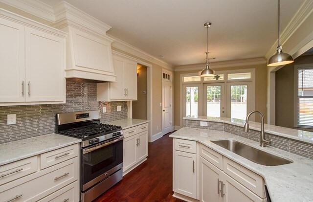 kitchen featuring backsplash, white cabinetry, stainless steel gas range, and a sink