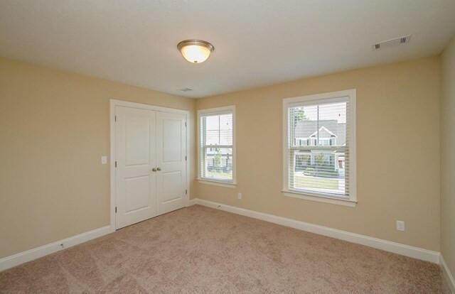 unfurnished bedroom featuring baseboards, a closet, visible vents, and carpet floors