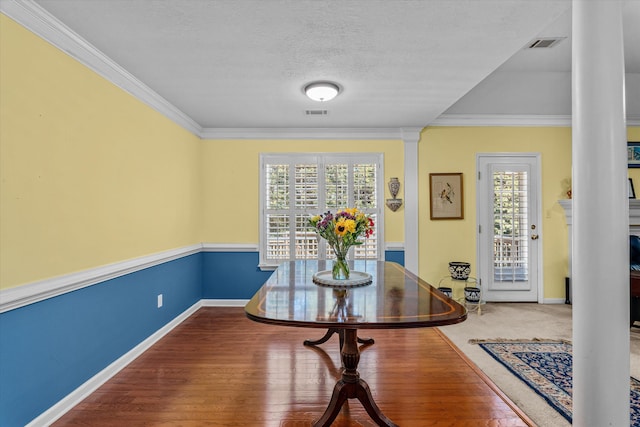 dining space with wood-type flooring, a textured ceiling, and crown molding