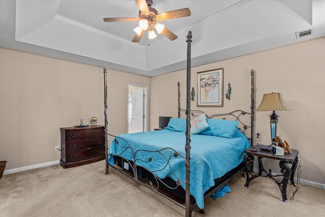 bedroom featuring light colored carpet, a raised ceiling, and ceiling fan