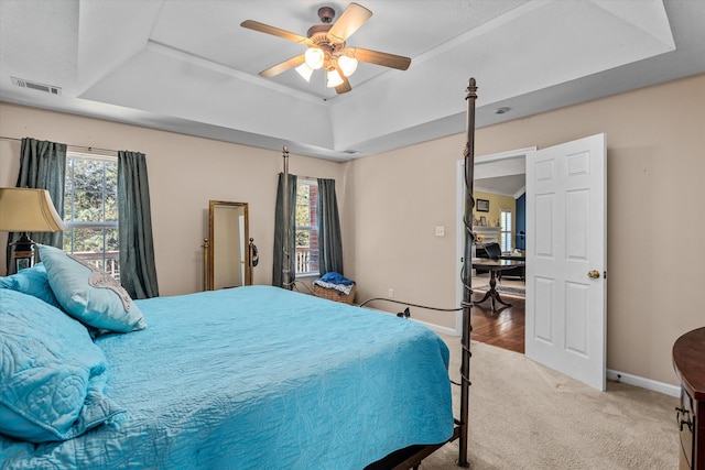 carpeted bedroom featuring a tray ceiling and ceiling fan