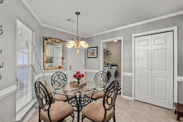 tiled dining area featuring a chandelier, washer and clothes dryer, and ornamental molding