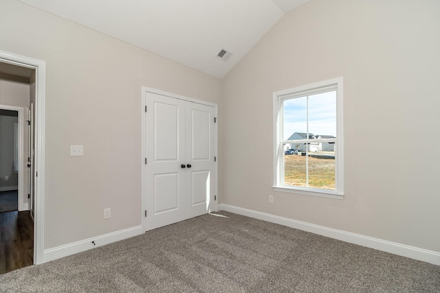 unfurnished bedroom featuring dark colored carpet, vaulted ceiling, and a closet