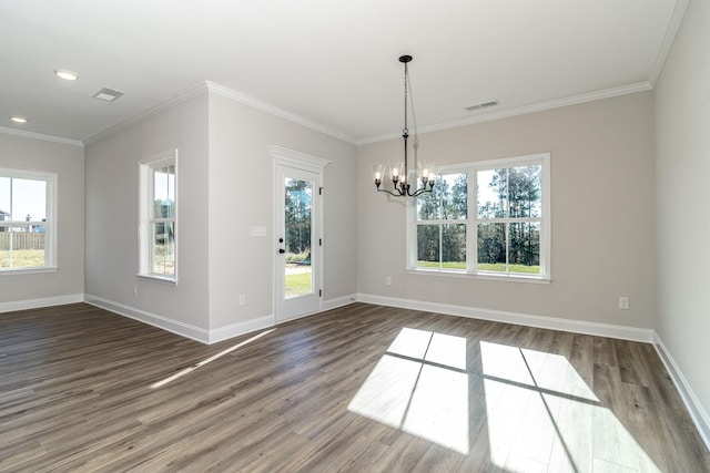 empty room featuring crown molding, a healthy amount of sunlight, hardwood / wood-style floors, and a chandelier