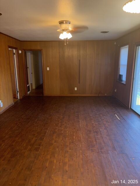 spare room with wooden walls, ceiling fan, and dark wood-type flooring