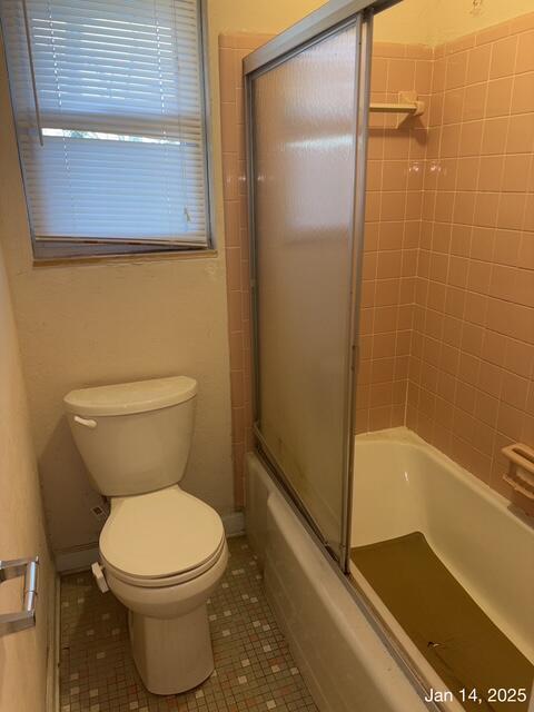 bathroom featuring toilet, tile patterned flooring, and shower / bath combination with glass door