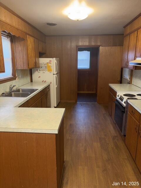 kitchen featuring white appliances, dark wood-type flooring, kitchen peninsula, backsplash, and sink