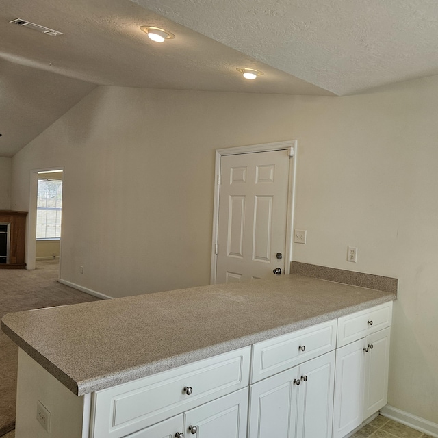 5102 Wheeler Lake Rd, Augusta, GA 30909 - kitchen featuring a peninsula, white cabinetry, vaulted ceiling, baseboards, and a textured ceiling