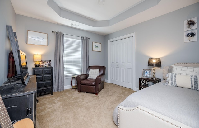 carpeted bedroom featuring a closet and a tray ceiling