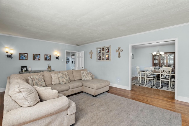 living room with wood finished floors, baseboards, an inviting chandelier, a textured ceiling, and crown molding