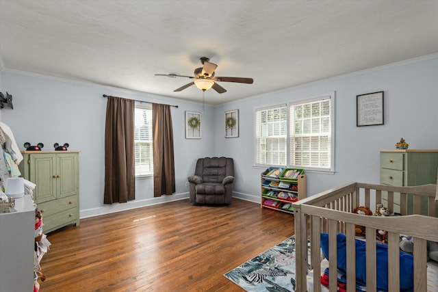 bedroom featuring a crib, crown molding, baseboards, and wood finished floors